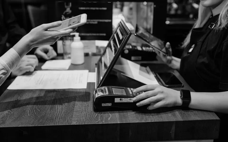 Customer paying at a cafe counter, phone out and card terminal ready