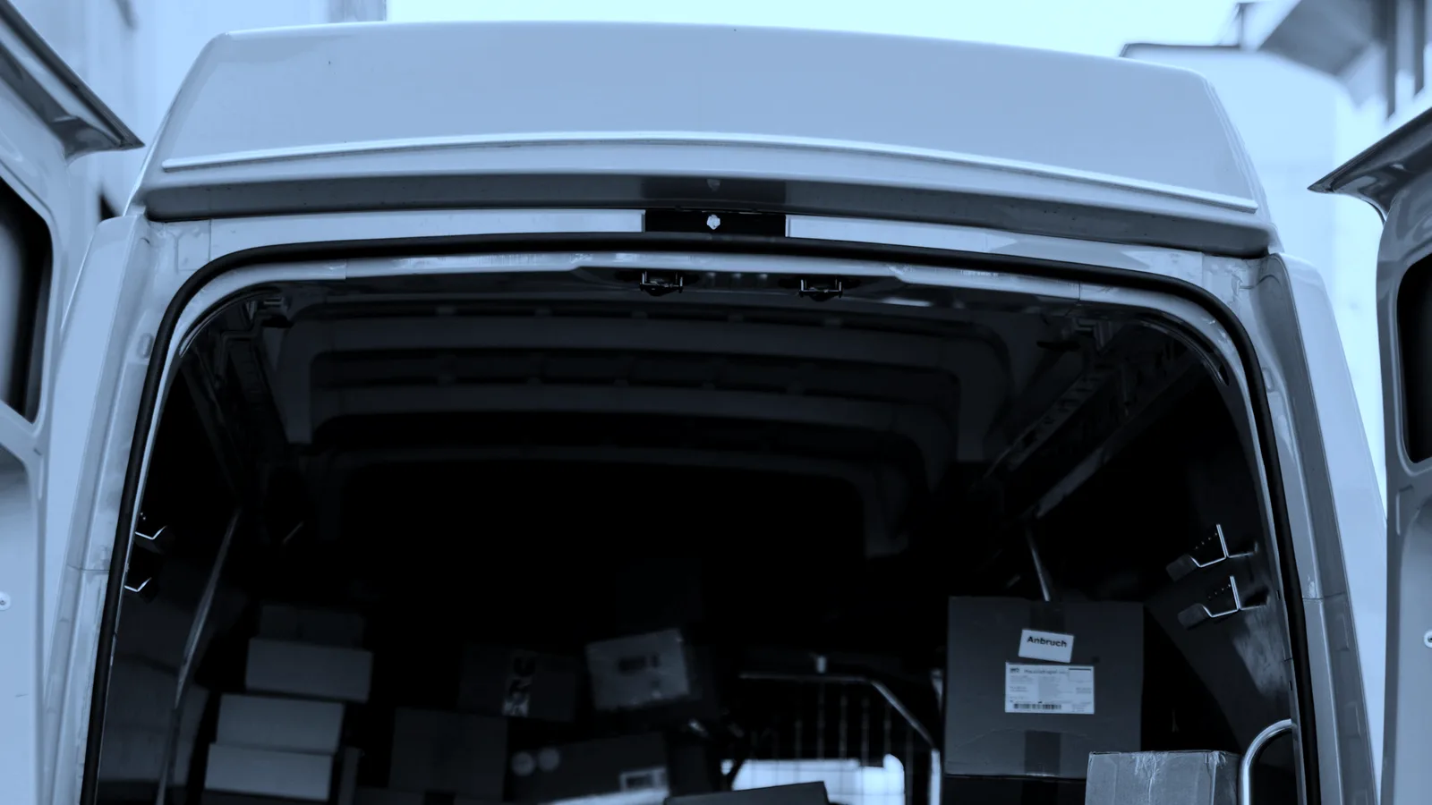 Boxes being loaded into the back of a van, tinted blue