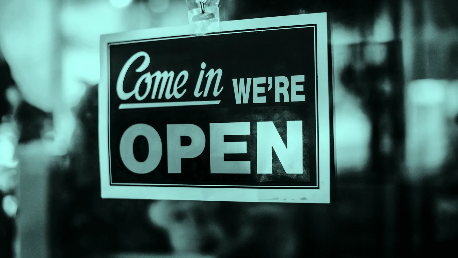 An open sign hanging in a shop door, tinted teal