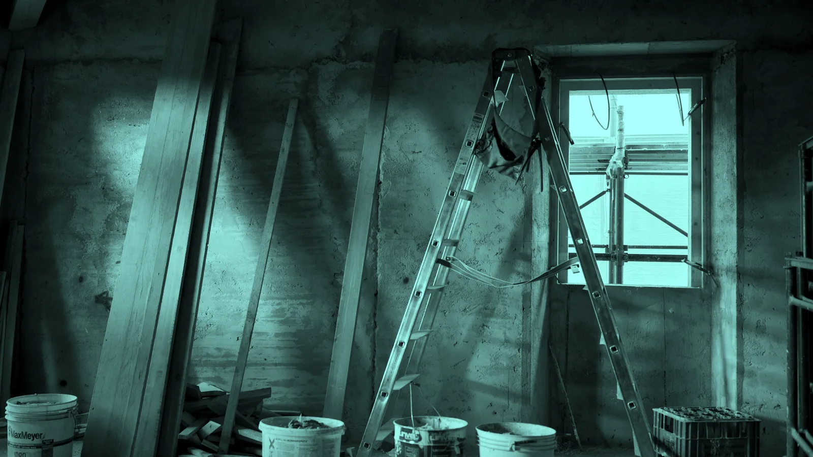 A gutted room mid-renovation with exposed brick, tinted teal