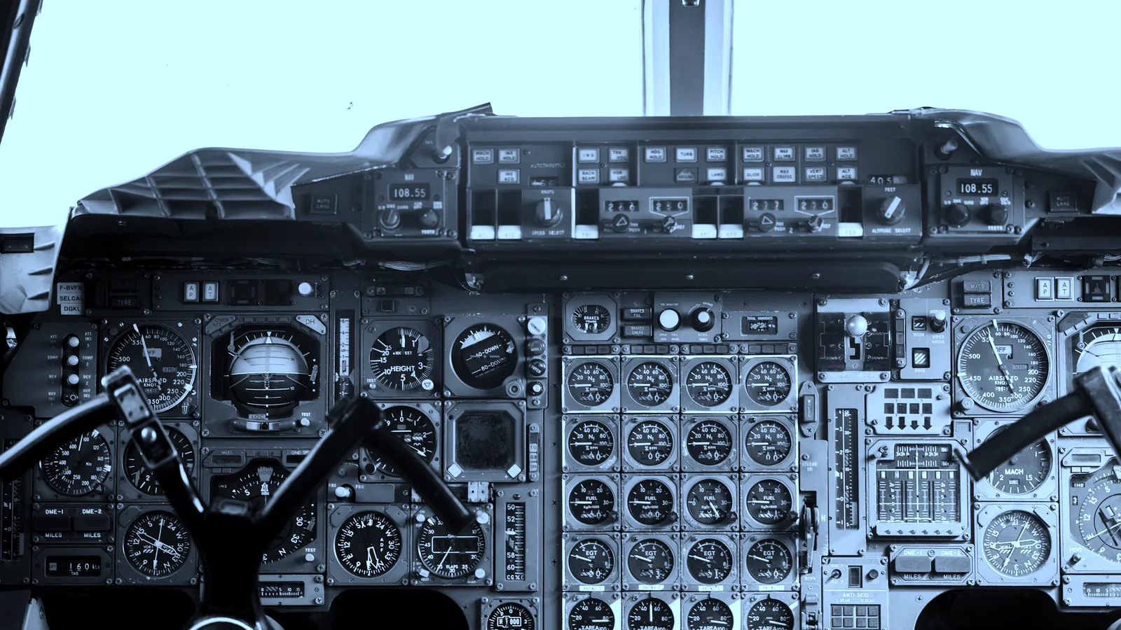 An aircraft instrument panel covered in gauges and switches, tinted blue